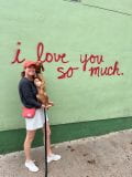 JJ Penny holding her dog outside of the I Love You So Much mural in Austin